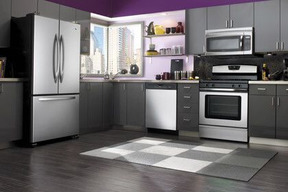 front view of a modern kitchen with grey cabinetry and stainless steel appliances