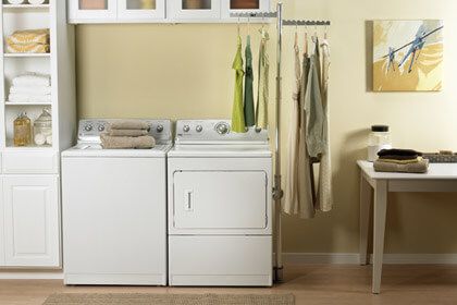 laundry-rooms front view of a modern laundry room with yellow walls, white washer and dryer, and various yellow and white accents