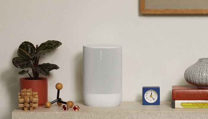 A Sonos speaker on a natural wooden dresser at home.
