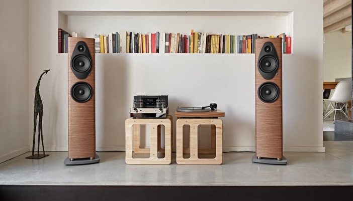 A set of speakers and record player in front of a bookshelf.