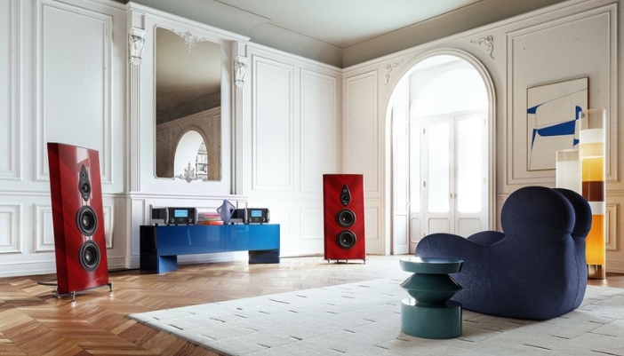 A vintage inspired living room with red wood style speakers and a modern couch.
