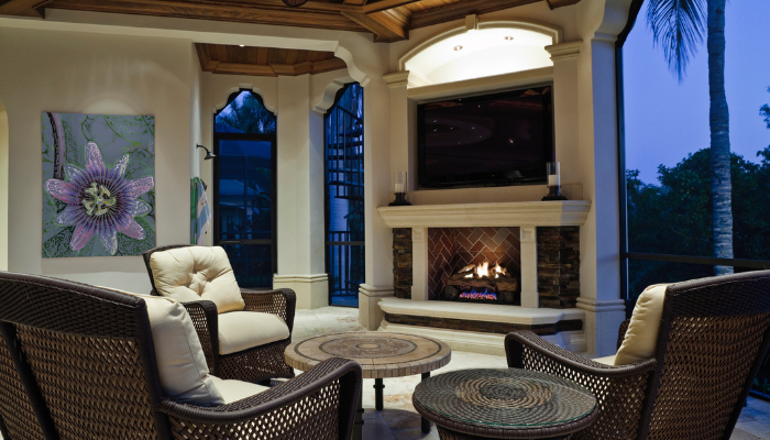 tv mounted above an outdoor fireplace under a patio in a luxury home