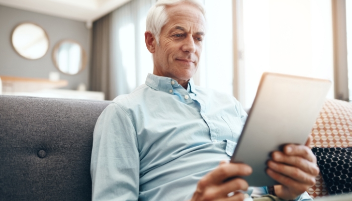 Man sitting on couch looking at tablet