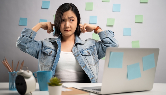Woman sticking fingers into her ears because of all the office noise