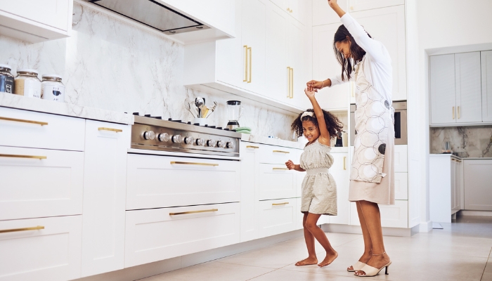 Mom and daughter dancing in luxurious, modern kitchen