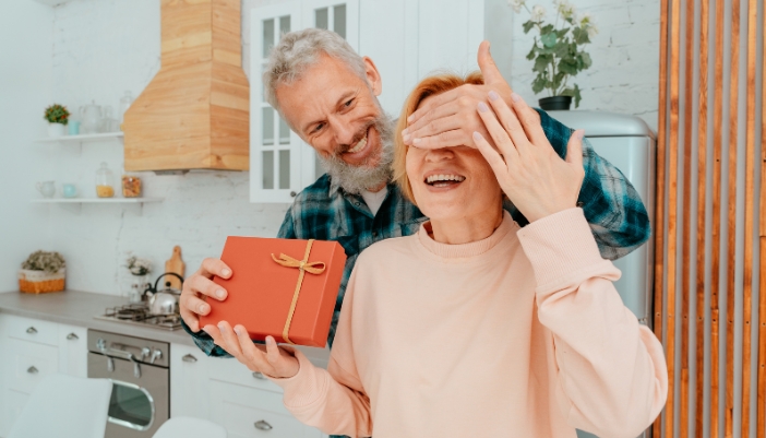 Man giving woman present with her eyes closed
