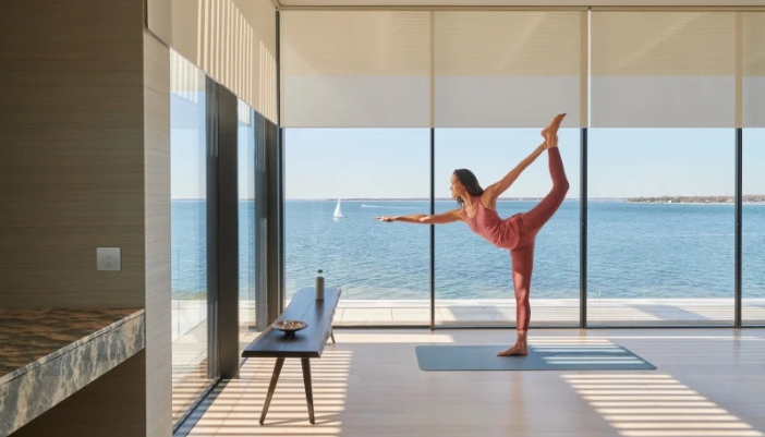 A woman in pink athletic gear does yoga in her home.