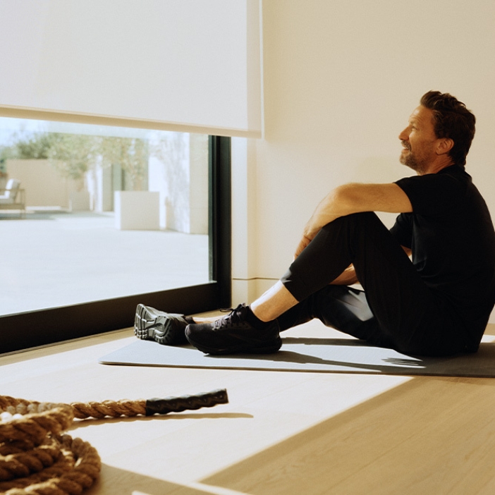 A man takes a break while working out and looks out his automated shade window.