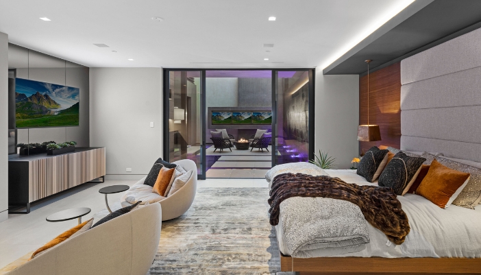 A gray bedroom lit with in-ceiling lighting.