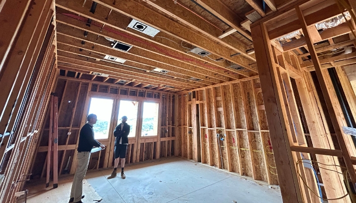 The interior of a home being built and two men stand in the room.