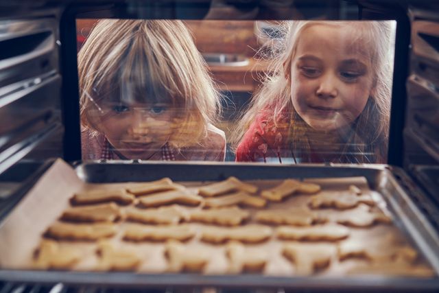 two kids looking inside an oven filled with baking cookies, view from inside the oven