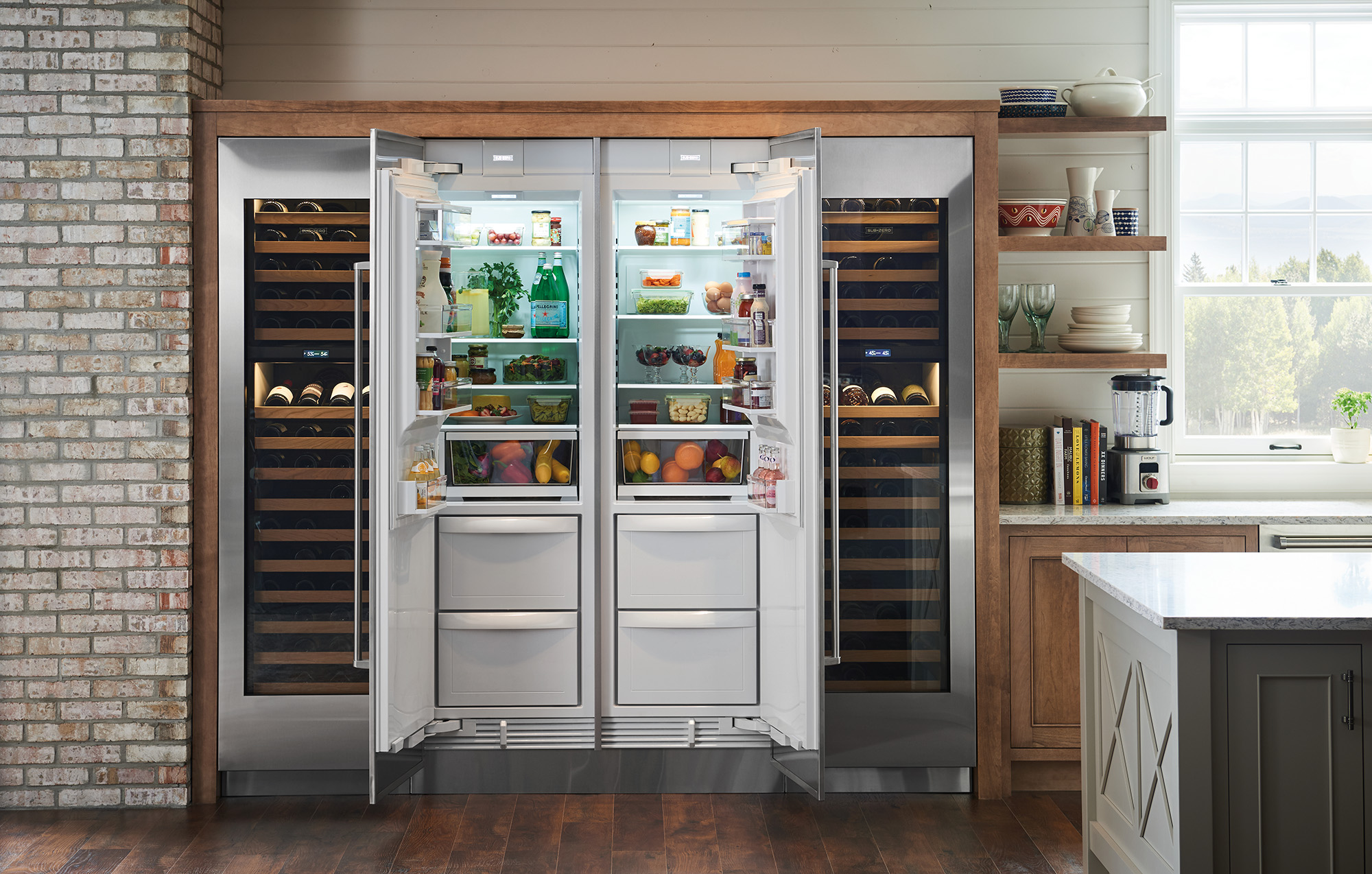 A side by side Sub Zero refrigerator is surrounded by Sub Zero wine coolers in a luxury kitchen