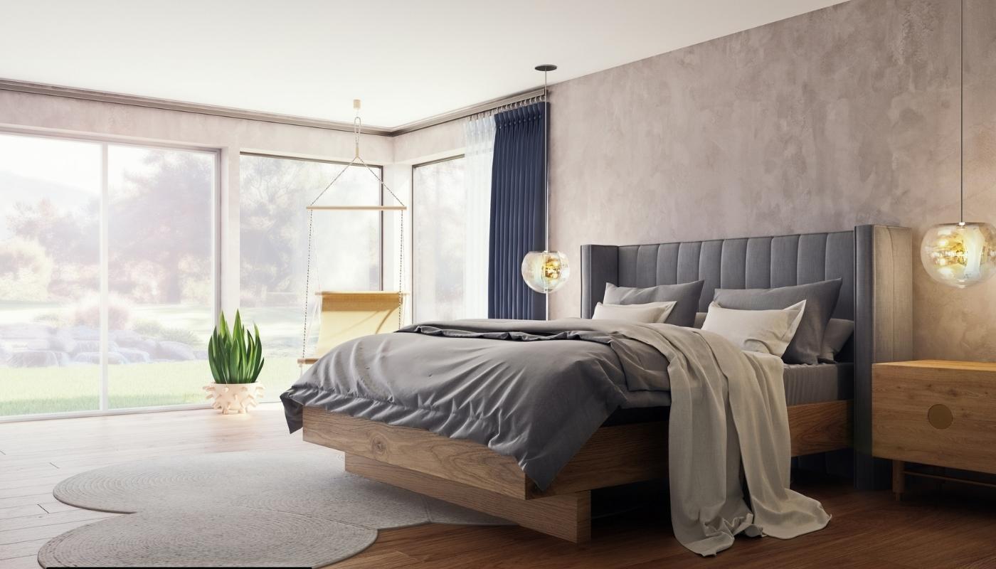 Grey upholstered bed in modern minimalist bed room with large windows and a plant