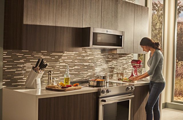 front view of a woman cooking on a slide in range in a modern kitchen
