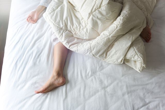 View of a person sleeping too hot on a bed