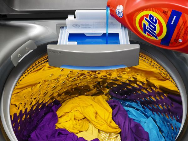 Tide laundry detergent pouring into a top load washer 