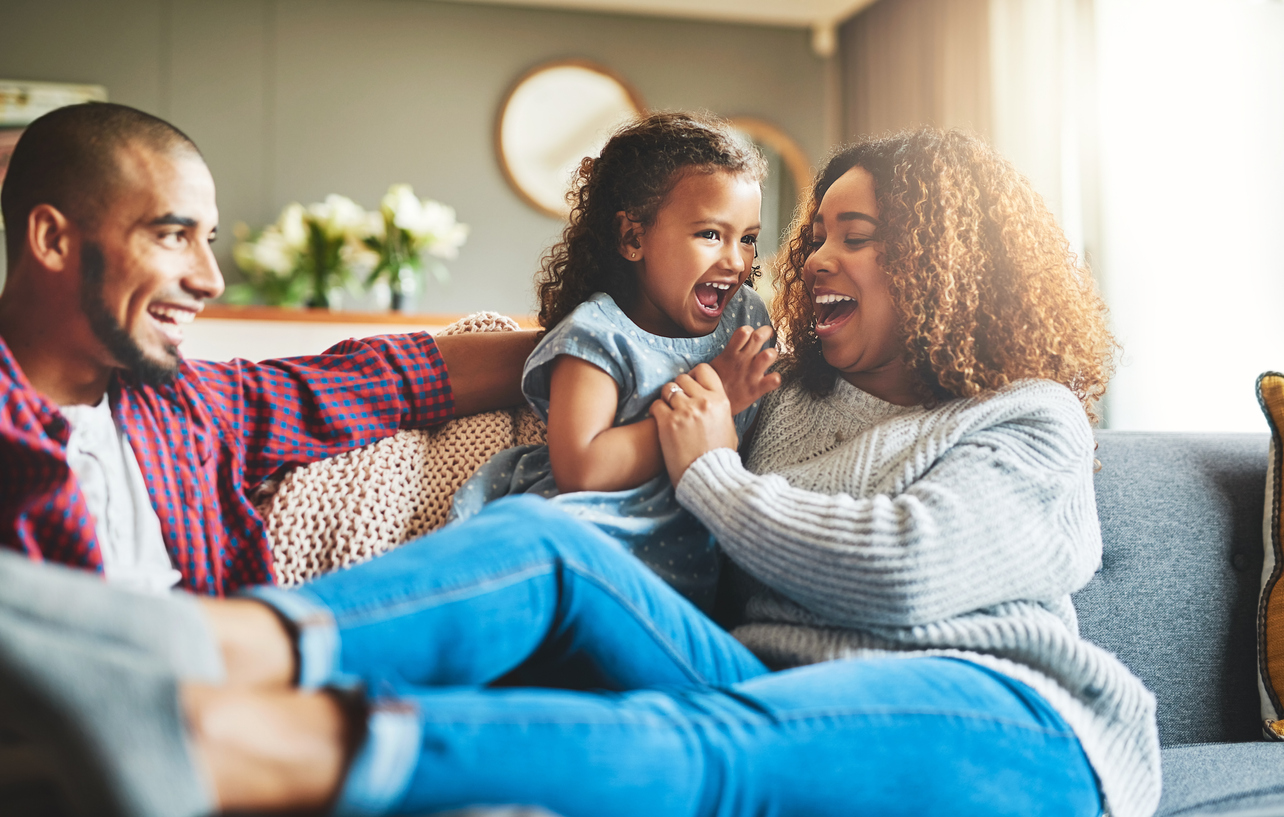 parents embrace daughter while lounging on the couch