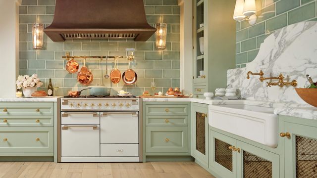 Front view of a modern farmhouse kitchen with a light mint backsplash and cream colored appliances