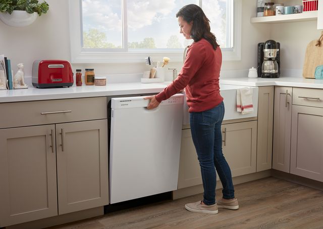 front view of a woman opening her white Amana front control dishwasher