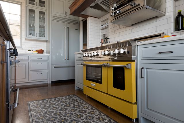 Low view of a modern kitchen with a yellow Viking range and light blue Viking french door refrigerator