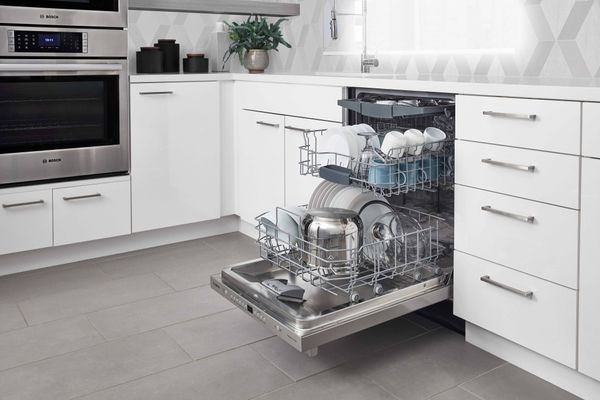 An open dishwasher with clean dishes inside in a kitchen with Bosch appliances