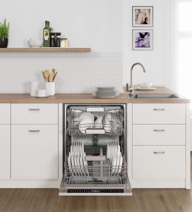 Front view of an opened Bosch dishwasher in a modern white kitchen.