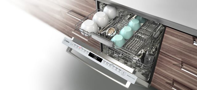 Close view of an opened Bosch dishwasher with the third rack pulled out and full of clean dishes