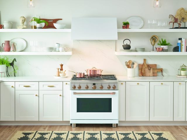 front view of a white cafe pro-style gas range built into white cabinetry in a modern kitchen