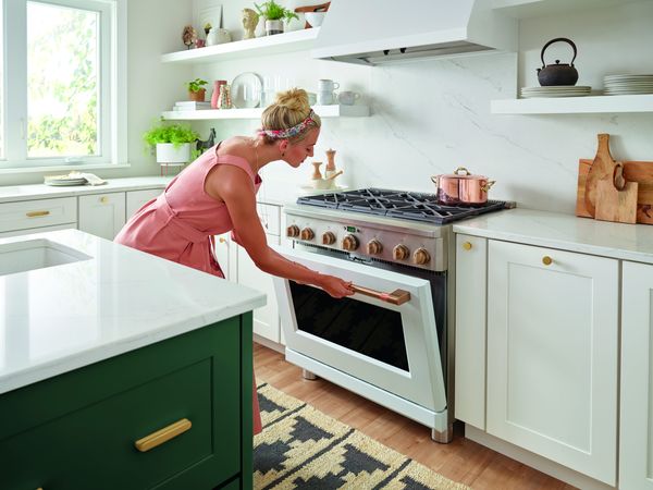 A woman opens the oven door of her Cafe stove