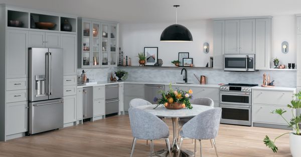 Contemporary kitchen with light grey cabinets, a round kitchen table, and stainless steel appliances.