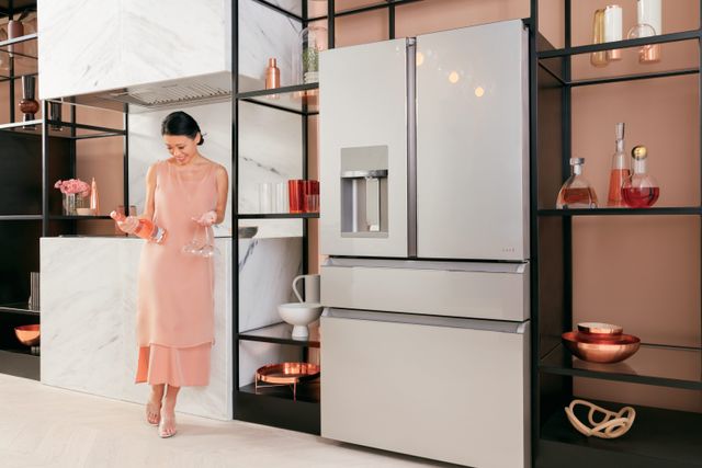 front view of a woman looking at a bottle of wine standing in front of her ge cafe stainless steel french door refrigerator