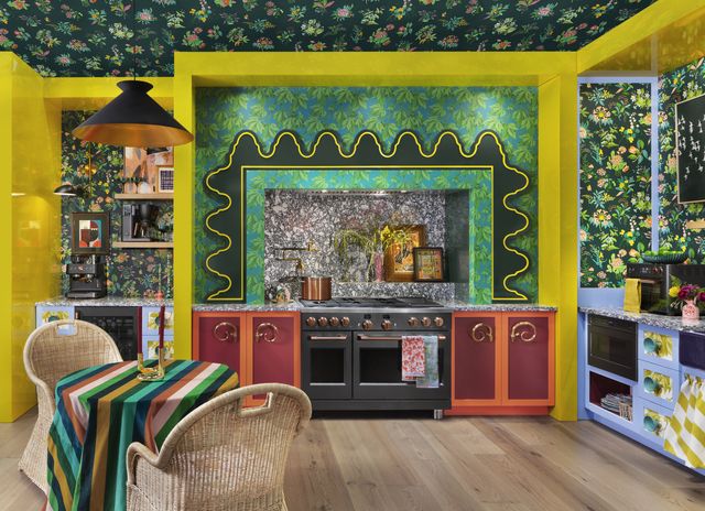 view of a green and yellow kitchen full of floral patterns, with a black cafe gas range built into bright cabinetry
