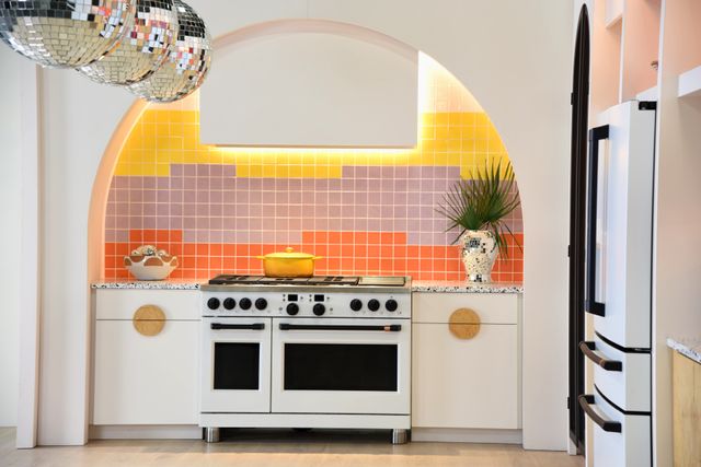 front view of a bright eclectic modern kitchen, with a sunset tile backsplash and a white cafe range