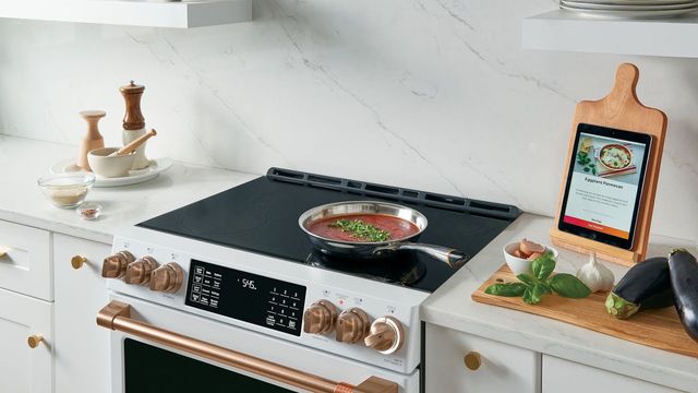 front view of a white cafe induction range with a pan of red sauce cooking on top