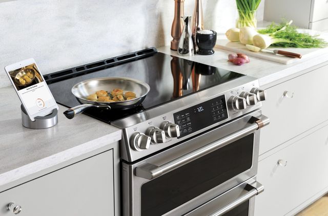 view of a cafe induction cooktop with a tablet showing a scallop recipe, and scallops cooking on a pan on the range