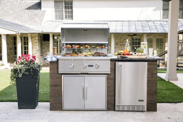 Front view of a built in Coyote grill in a modern outdoor kitchenette