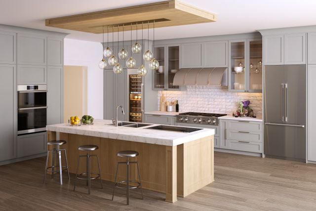 front view of a modern luxury kitchen with a large center island. The kitchen has all dacor appliances, with a dacor refrigerator on the right side in the foreground