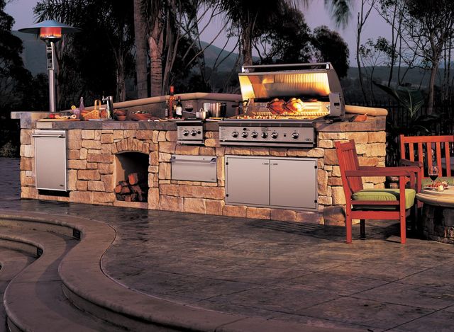front view of a modern outdoor kitchen with various outdoor appliances including a grill, side burner, and cabinets