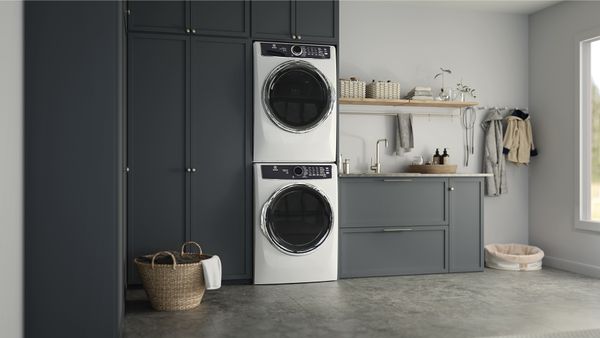 A stackable washer and dryer installed in the black cabinetry of a laundry room