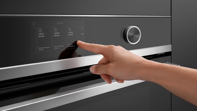 Close view of a person touching the touch screen on a Fisher and Paykel combi steam oven