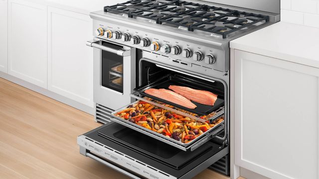 front view of an opened fisher and paykel range with fish and veggies on the racks, pulled out