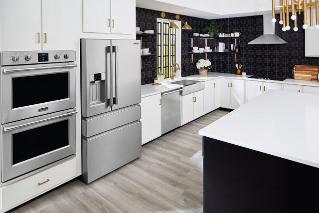 Angled view of a luxury kitchen with a Frigidaire Professional French door refrigerator and double wall oven beside it