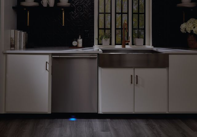 Front view of a dimmed kitchen with a Frigidaire stainless steel dishwasher 