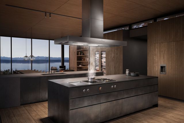 Front view of a contemporary kitchen with a Gaggenau cooktop and range hood with a pot boiling on the cooktop, and the steam being sucked into the range hood.
