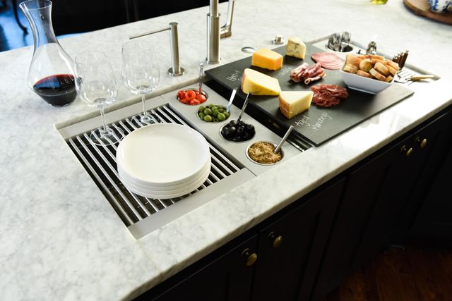front top view of a workstation sink being used as a serving station for cheese, meats, olives, breads, and wine