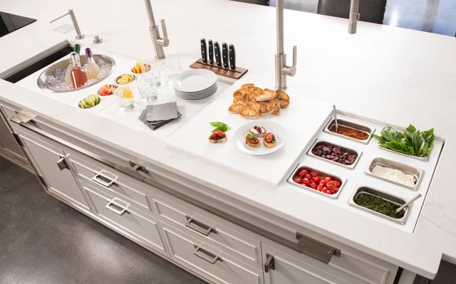 top view of a white workstation sink installed in a white kitchen island with storage cabinets below
