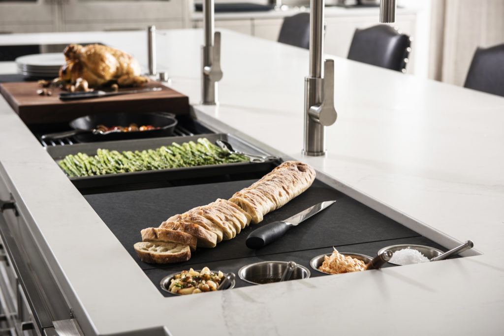 right side view of a workstation sink being used as a cooking and serving area for a chicken and vegetable dinner