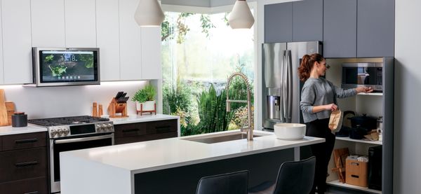 A woman cooks popcorn in her kitchen outfitted with stainless steel smart appliances