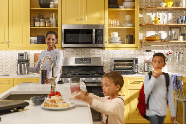 Front view of a family getting breakfast before school in a bright casual kitchen