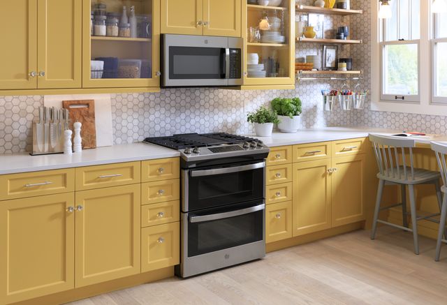 front view of a modern kitchen with yellow cabinets, white counters and backsplash, and stainless steel ge appliances